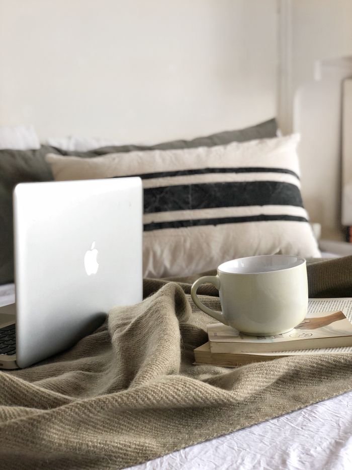 Relaxing scene with laptop and coffee on bed, perfect for a cozy day indoors.